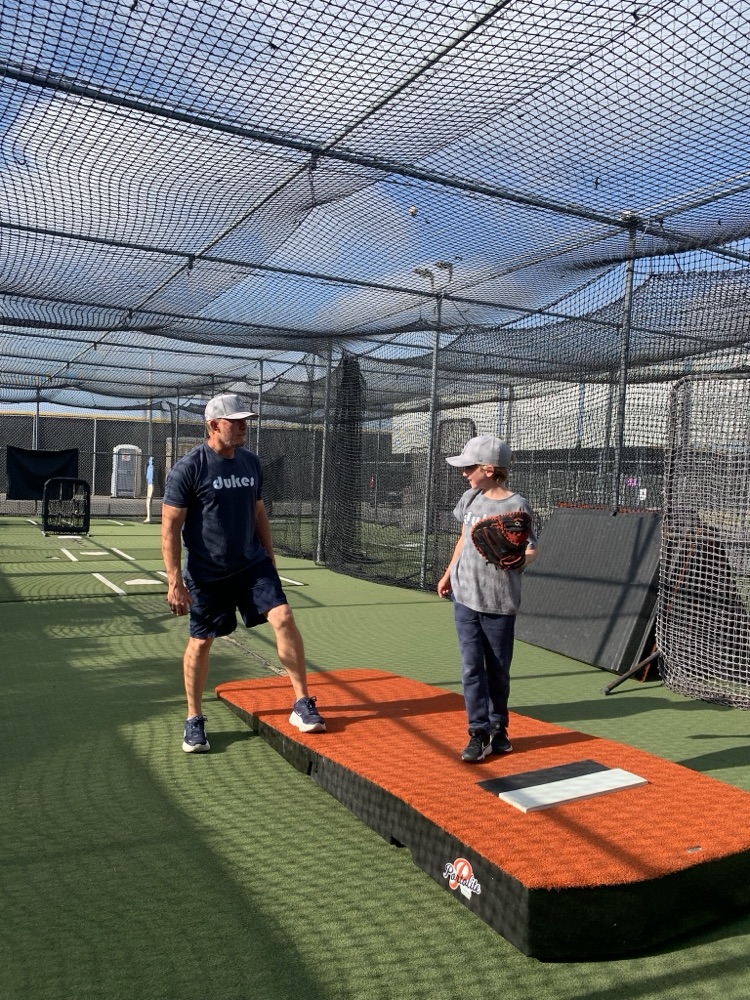A Dukes coach working with a player in the batting cage